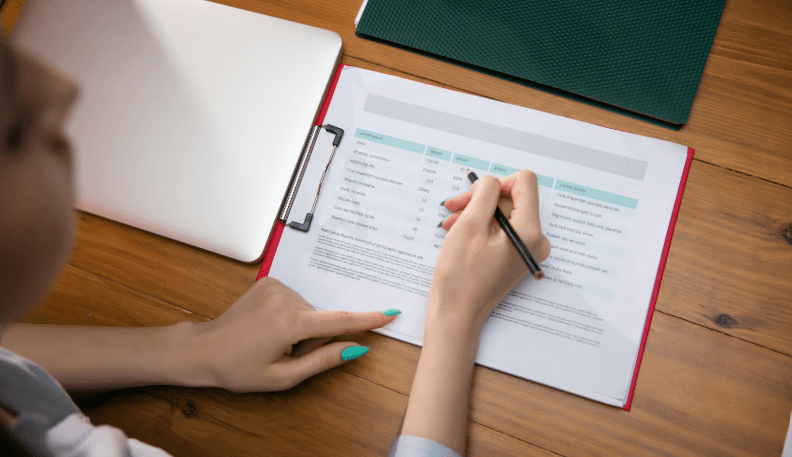 A clinician reviewing a written workplace assessment report at a desk